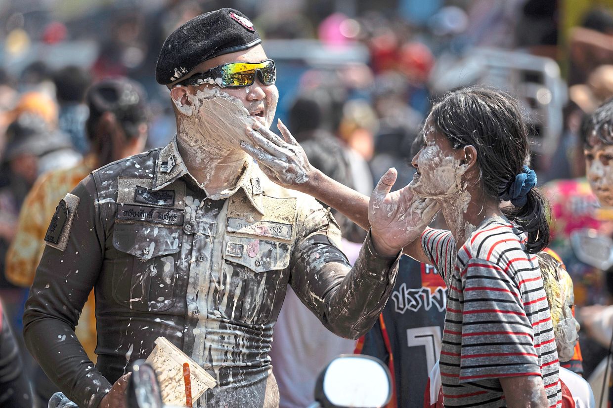 A participant gently applies powder to a Thai police officer’s face during Songkran festivities in Prachinburi province. — AP