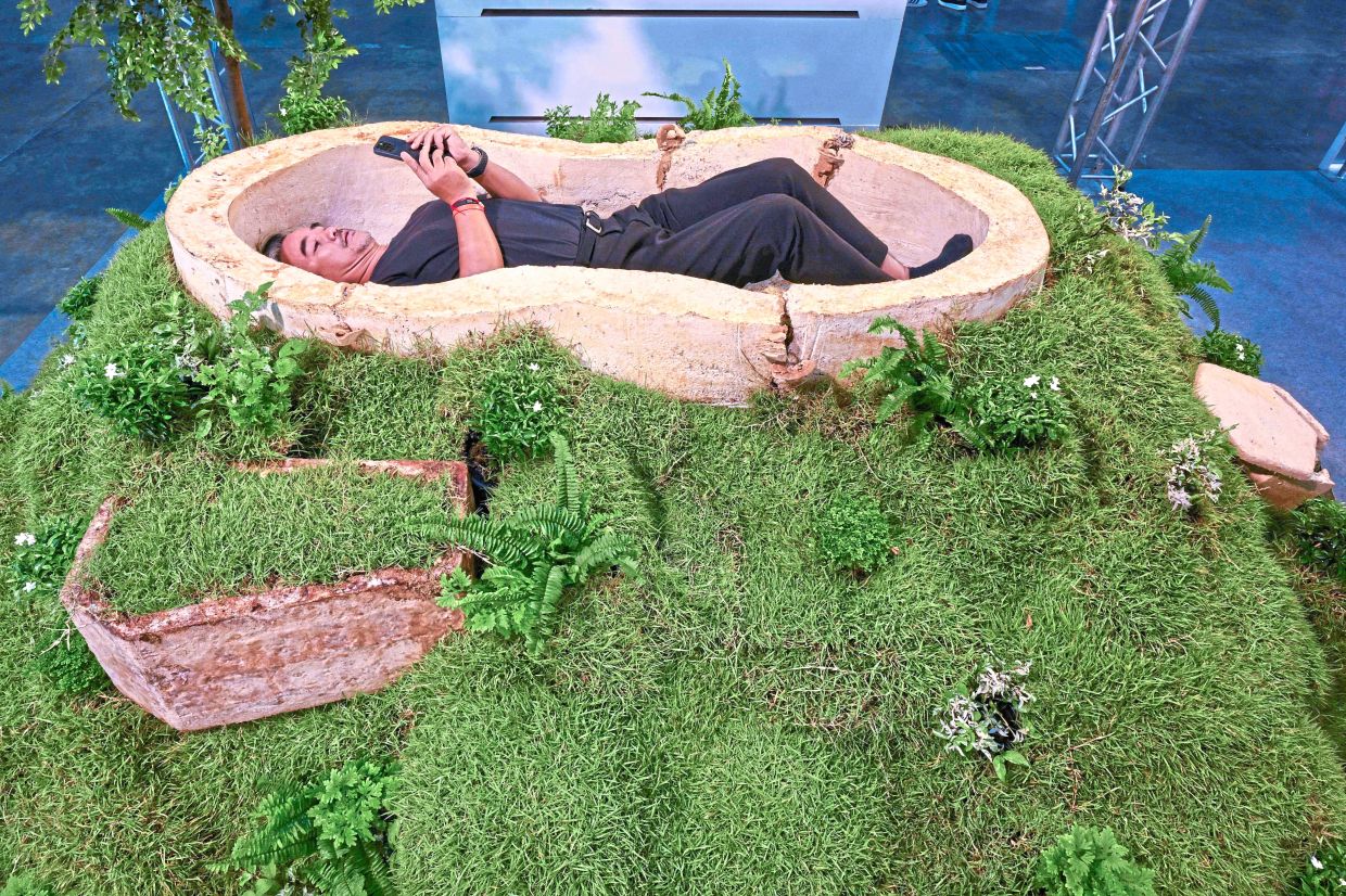 Eco-friendly pick: A visitor testing a coffin made of mycelium. — AP