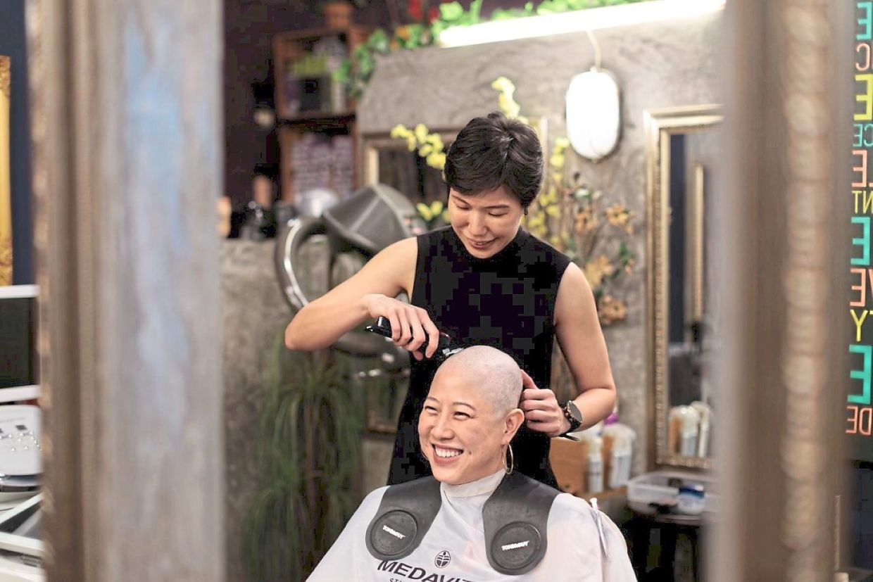 When Lau's (seated) hair began to fall out during chemotherapy, she confided in Lim (standing) her fear of going through it alone. Photo: Sarawak Breast Cancer Support Group