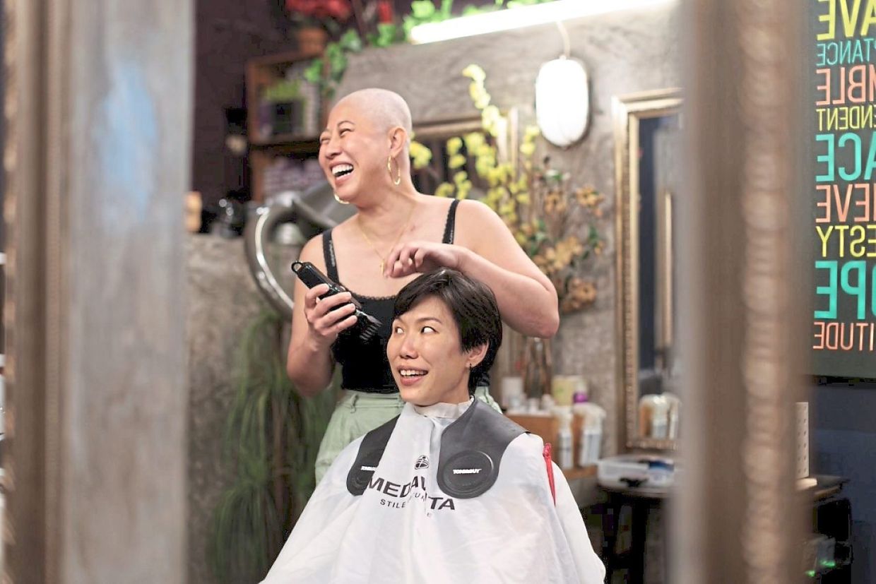 Lim (seated) getting a helping hand from Lau to shave her hair off to support cancer survivors in Sarawak. Photo: Sarawak Breast Cancer Support Group