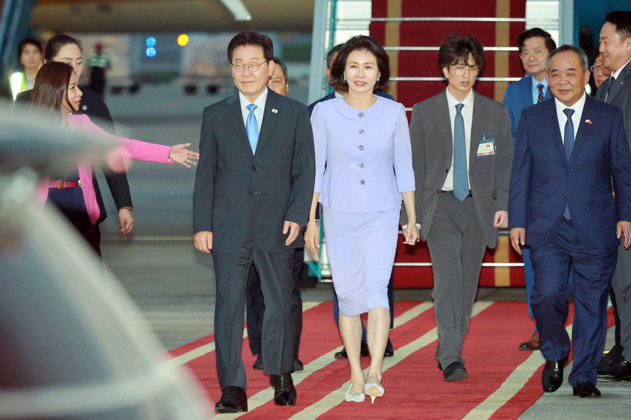 South Korea's President Lee Jae Myung (centre L) and his wife Kim Hea Kyung (centre) disembark from the plane upon their arrival at Noi Bai International Airport in Hanoi on April 21, 2026. -- Photo by YONHAP / AFP