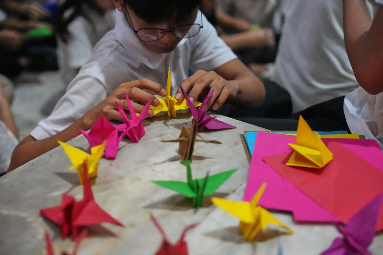 A Filipino boy makes origami cranes during an event supporting calls for peace and an end to war by Pope Leo XIV, inside a Catholic church in Quezon City, Philippines, Tuesday, April 21, 2026. -- AP Photo/Aaron Favila