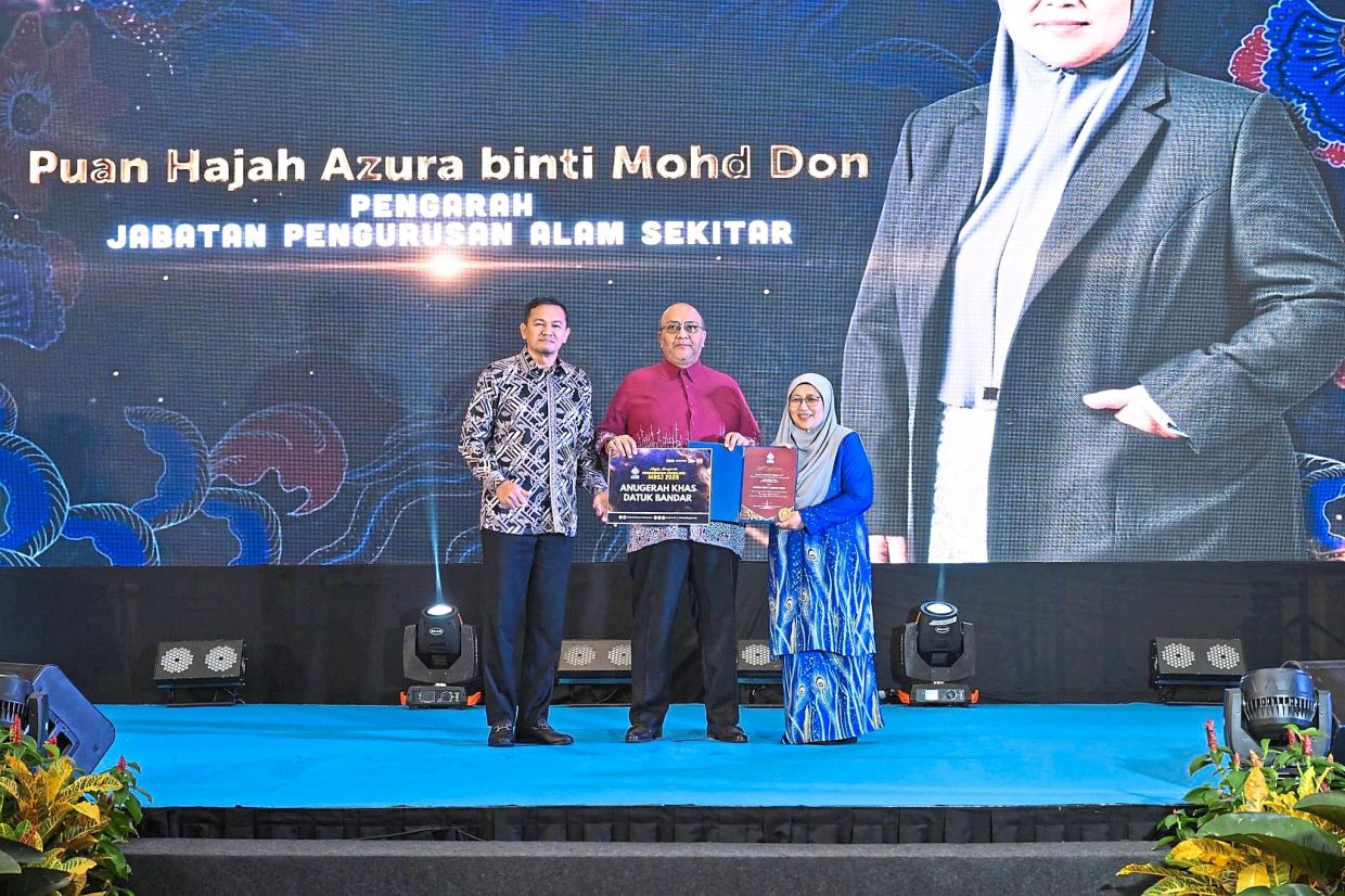 Amirul Azizan (centre) presenting the Mayor’s Special Award to Azura. With them is deputy mayor Mohd Zulkurnain.