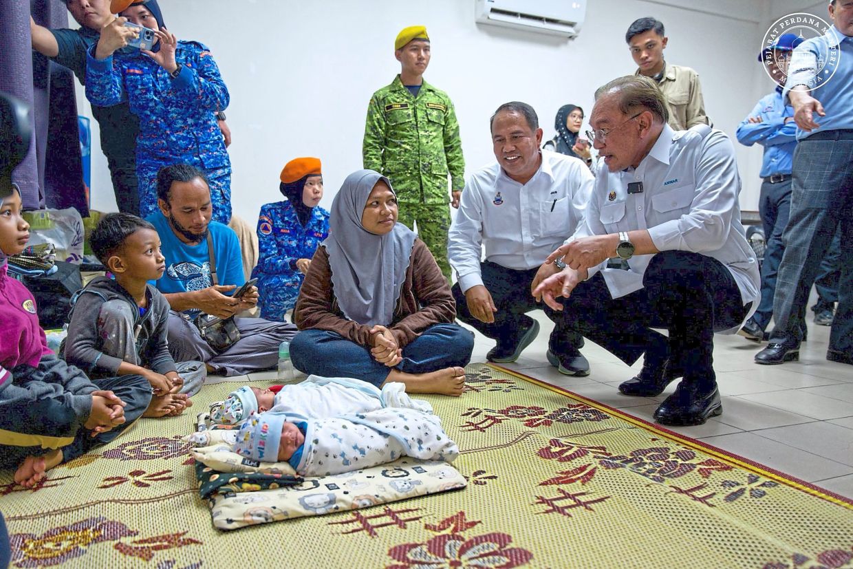 Hope and new life: Anwar enquiring on the well being of fire victim Razma Ismail and her 22-day-old twins when he visited the temporary evacuation centre at the Taman Batu Sapi People’s Housing Project hall.