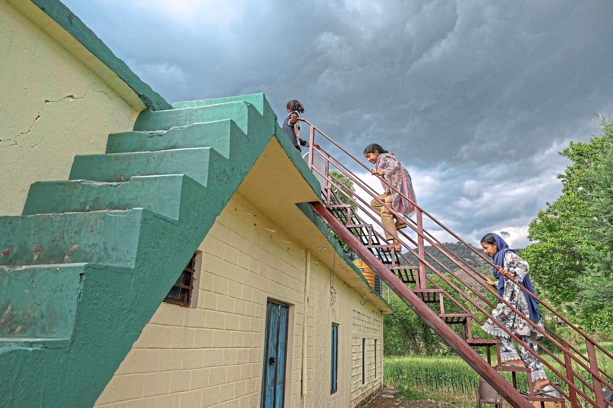 Simple joys: Children climbing a rooftop at Kasaliyan village, near the Line of Control in the frontier district of Poonch. — AFP