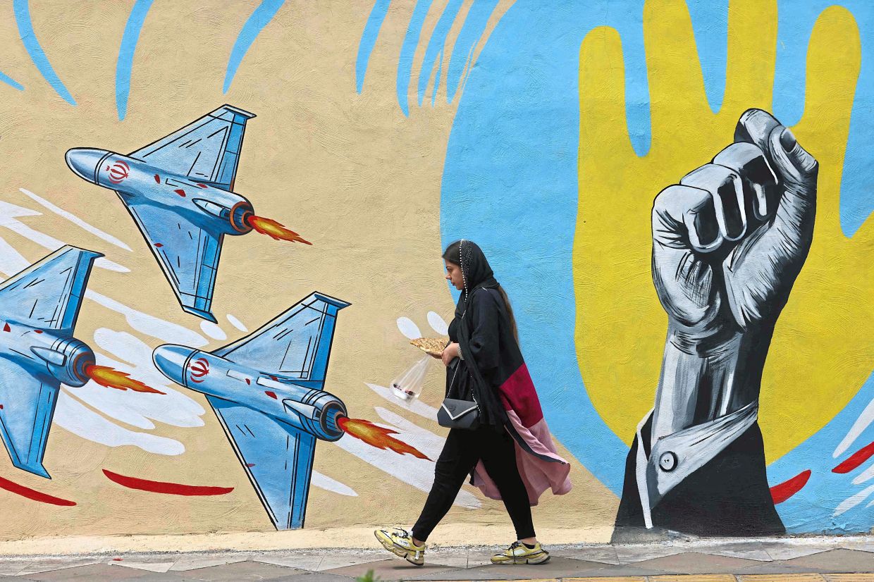 A woman walking past a newly-painted anti-US and anti-Israel mural in Tehran. Photo: AFP