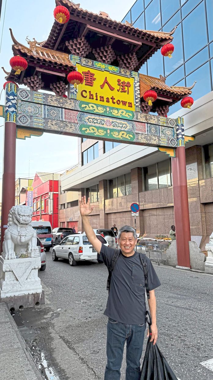 The writer standing in front of the Chinese archway known as the paifang, a symbolic landmark of Chinatowns around the world.