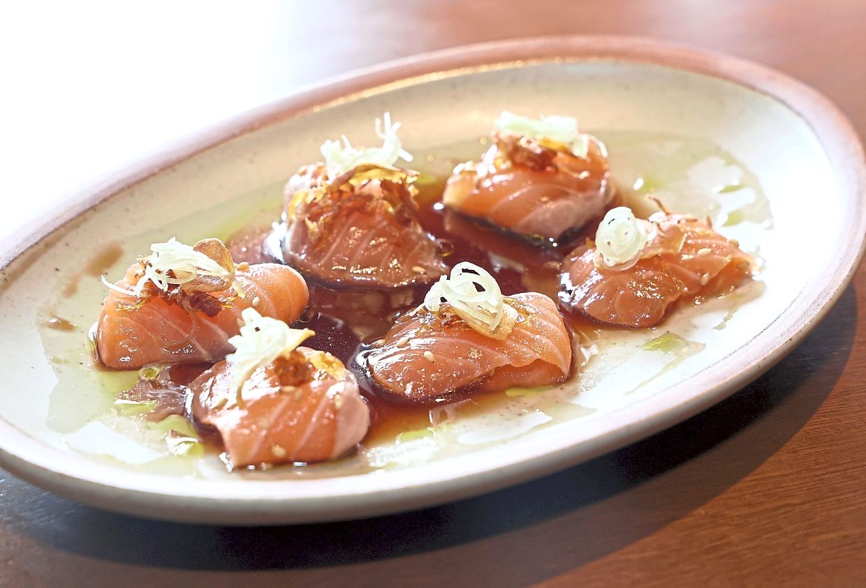 The salmon's freshness is boosted by the yuzu ponzu, fried shallots and pandan oil that surround it. — ART CHEN/The Star