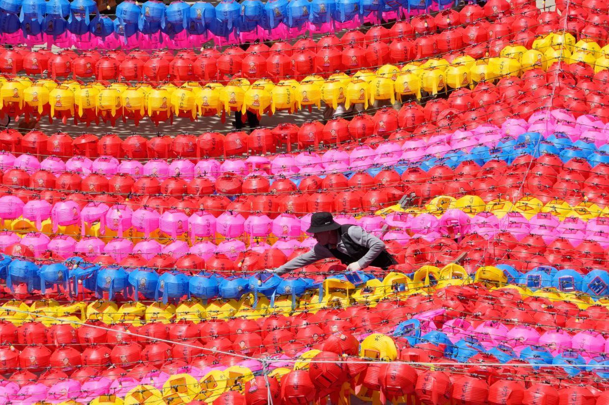 A work adjusts lanterns for the upcoming celebration of Buddha's birthday on May 24, better known as Wesak Day, at Jogye temple in Seoul, South Korea, on Friday, April 24, 2026. -- AP Photo/Ahn Young-joon