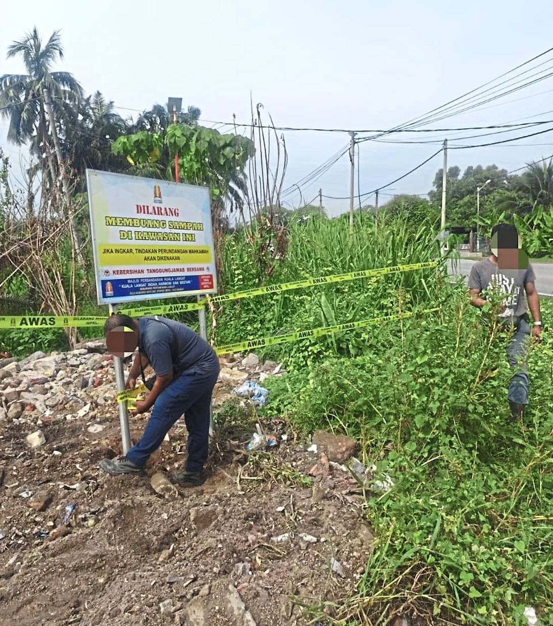 A local council worker installing a warning sign along Jalan Sungai Nangka in Banting to deter illegal dumping.