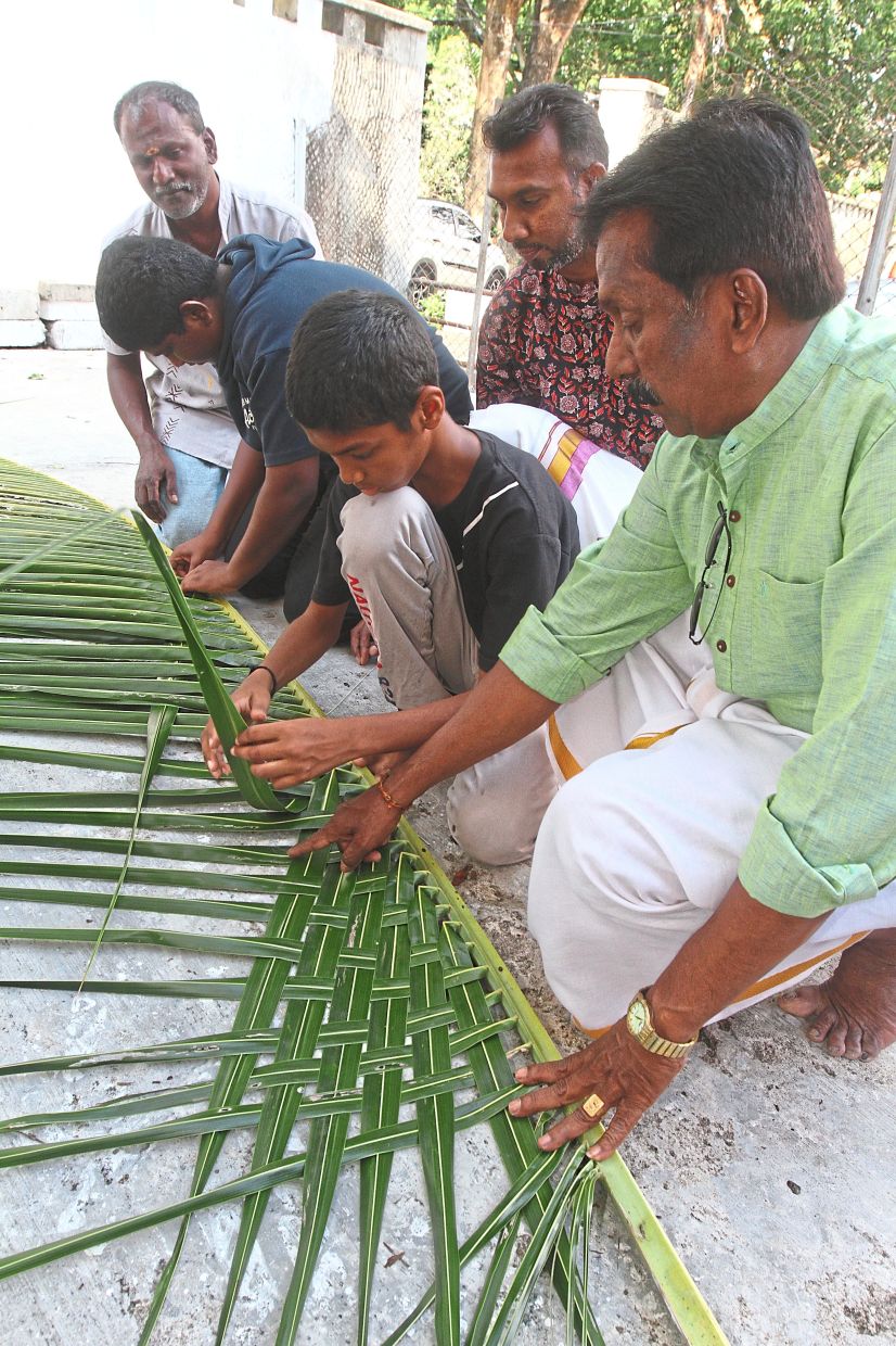 (From right) Krishnan guiding Darmendran on weaving ‘mattai’ as Thanabalan (partly hidden) looks on. Photos: — LIM BENG TATT/The Star