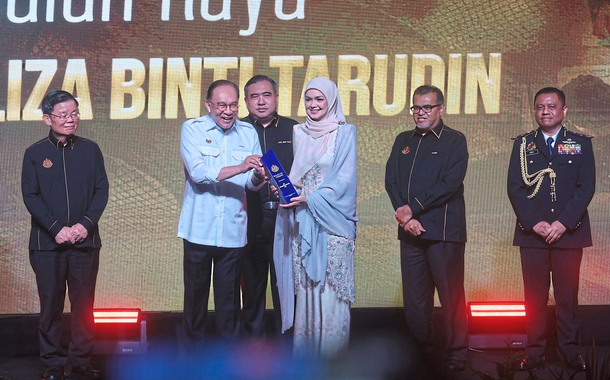 In recognition: Songstress Siti Nurhaliza receiving the Road Safety Icon award from Anwar during the JPJ anniversary celebration at Stadium Batu Kawan, Penang. Looking on are (from left) Chow, Loke and Aedy. — ZHAFARAN NASIB/The Star