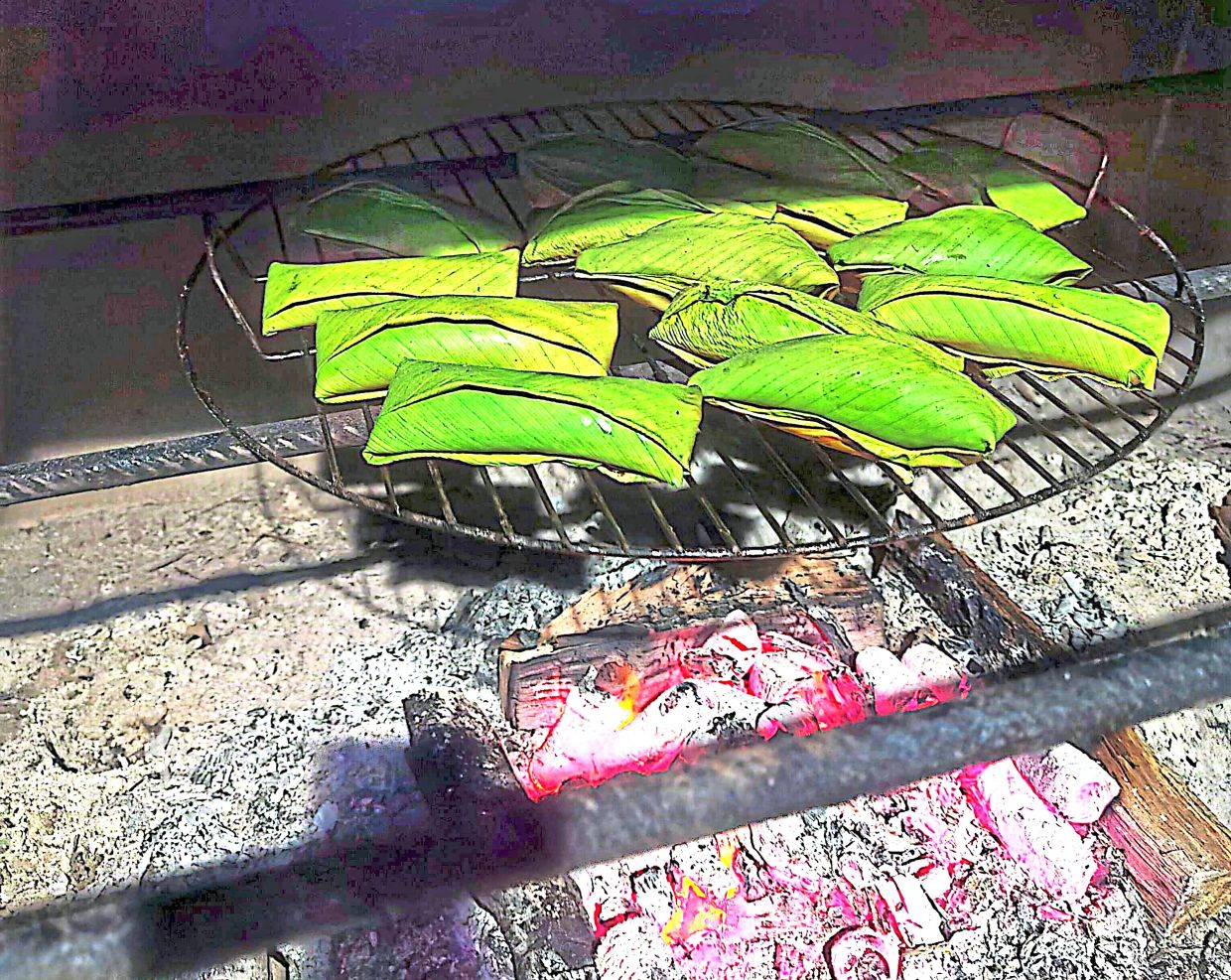 Parcels of wrapped durian being smoked over charcoal embers. — Photos from Information Department