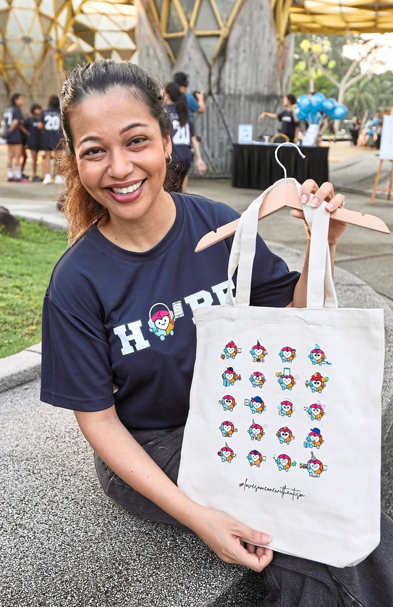 Isaacs holding a bag designed by individuals with autism at the charity carnival in Kuala Lumpur. — Photos: LOW LAY PHON/The Star