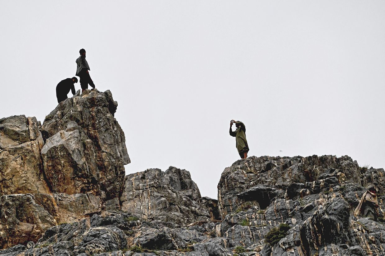An Afghan visitors take photos on a mountainside. Photo: AP