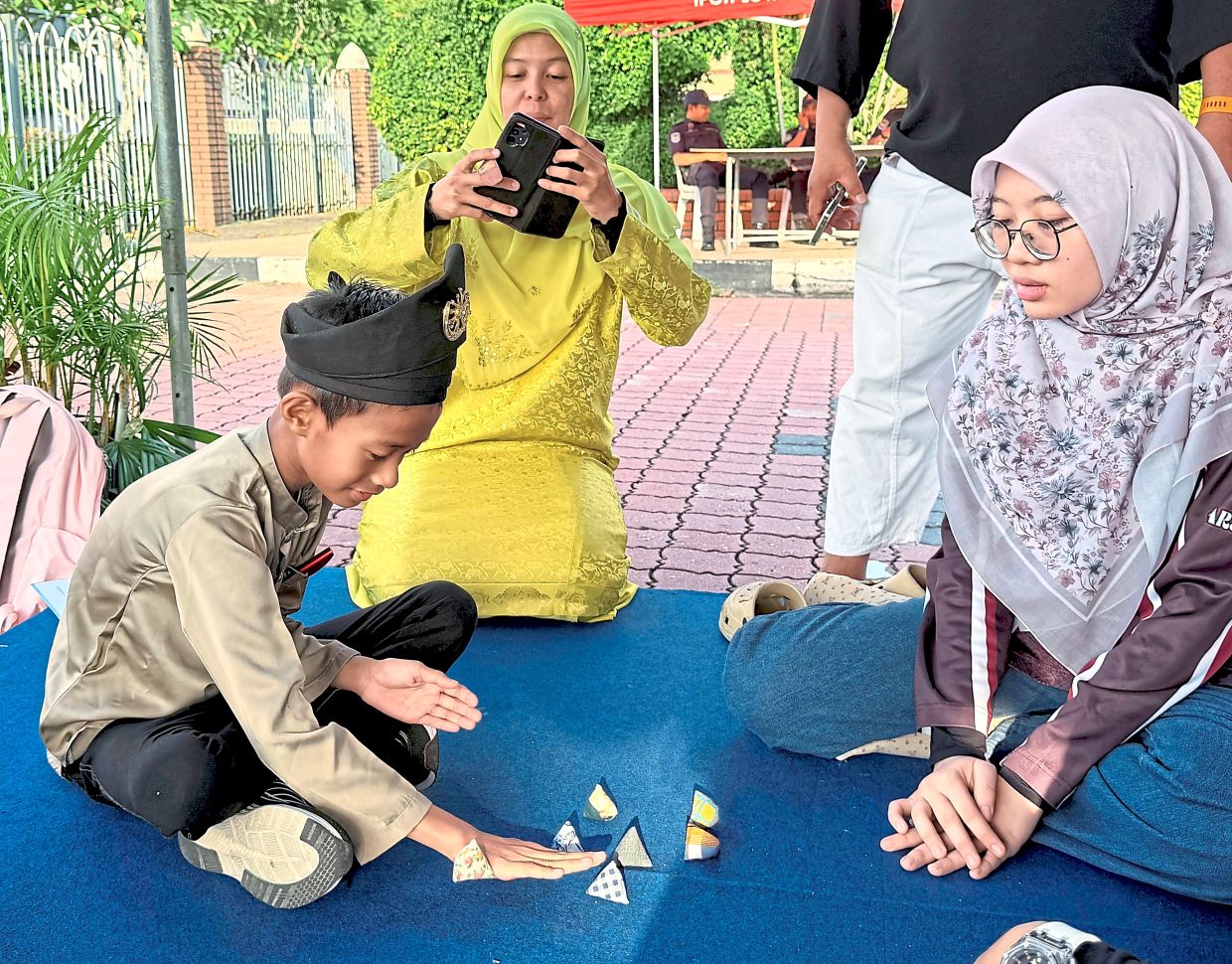 Youngsters trying their hand at ‘batu seremban’ (above) and ‘congkak’ (below) at the community sports event held in conjunction with Ipoh Low-Carbon Day. 