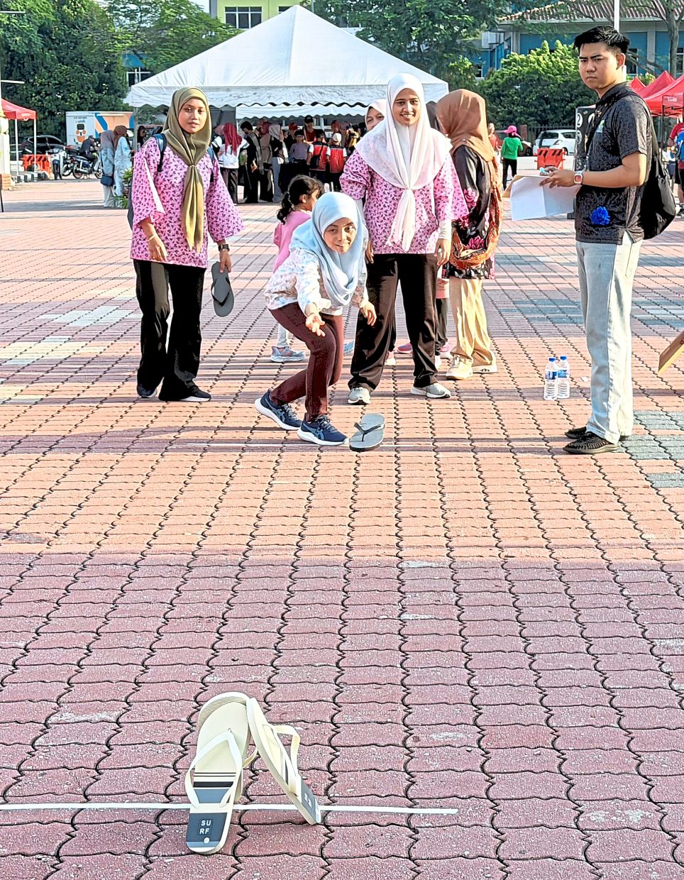 Participants testing their aim and throwing skills using slippers. 
