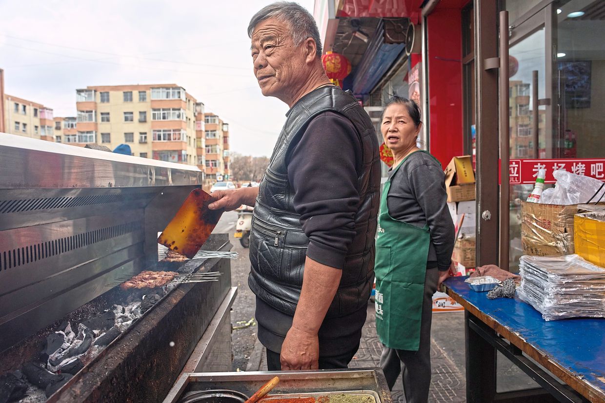 Yang preparing skewers of barbecued meat at his restaurant in Datong. — AP