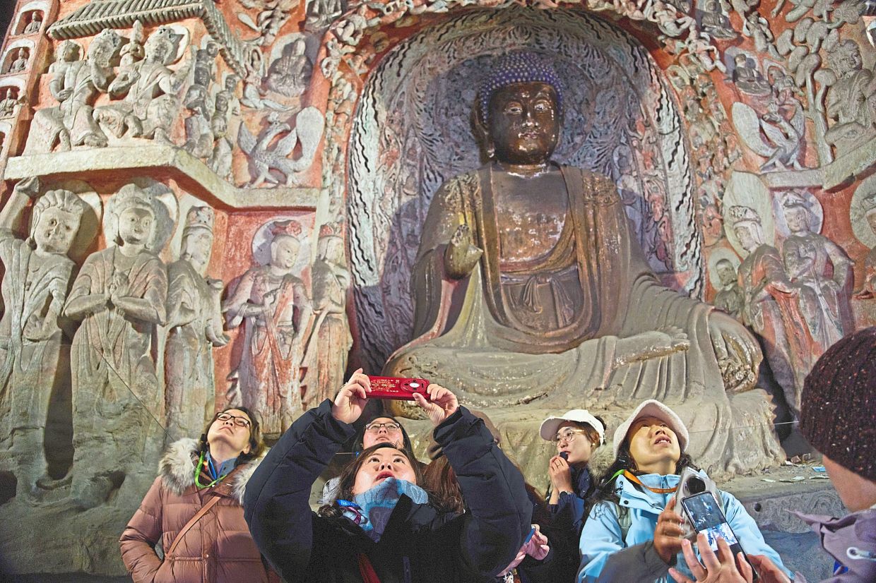 Tourists visiting the Yungang Grottoes in Datong. — AP