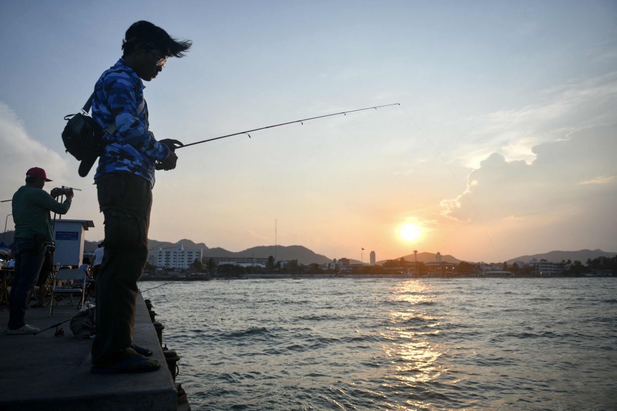 A man fishes during sunset in Hua Hin. -- Photo by Amaury PAUL / AFP