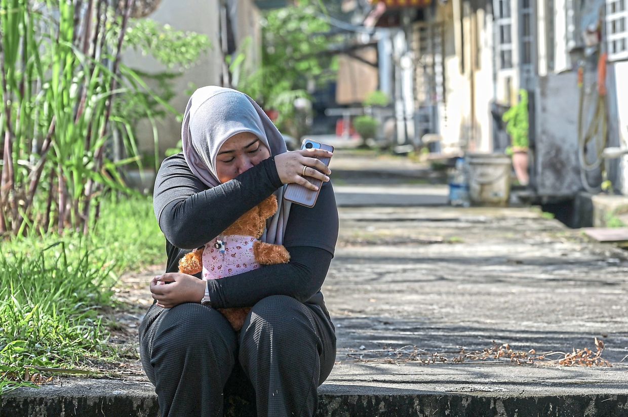 Nordina clutching her daughter’s toy. — Photo courtesy of Bomba/Bernama 