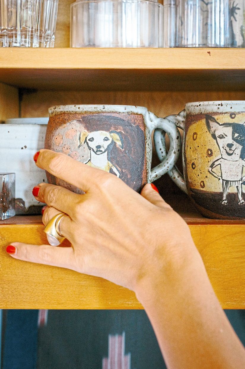 Pamer reaches for a mug with a design of her dog in the ceramics cabinet at her home. 