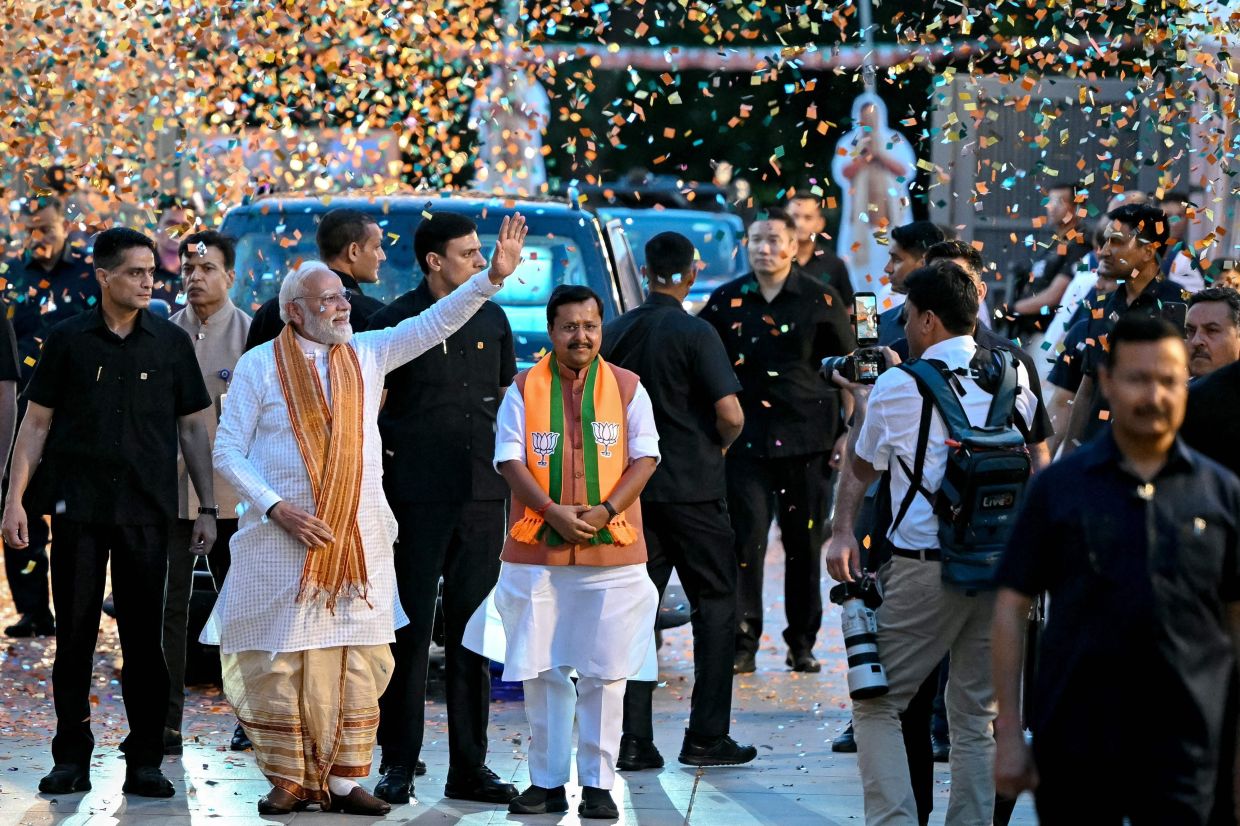 India's Prime Minister and Bharatiya Janata Party (BJP) leader Narendra Modi (2L) waves to supporters as he arrives at party headquarters in New Delhi on May 4, 2026. Modi claimed victory on May 4 in state elections in opposition-held West Bengal, where his party has never been in power before. -- Photo by Sajjad HUSSAIN / AFP