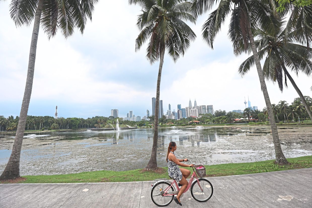 A woman enjoying a leisurely cycle along a dedicated path in Taman Tasik Titiwangsa.