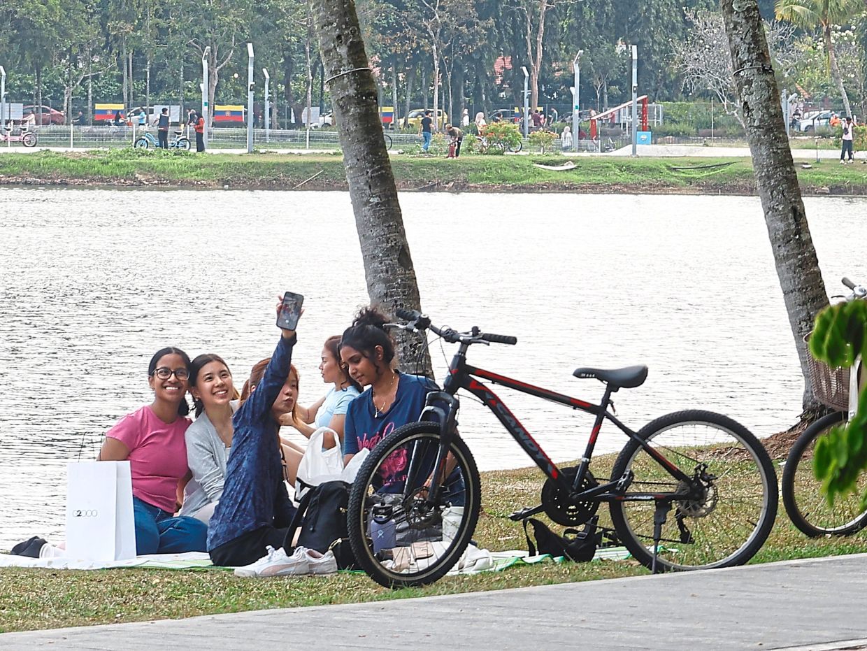 A group of young women taking a break to enjoy a picnic by the lake.