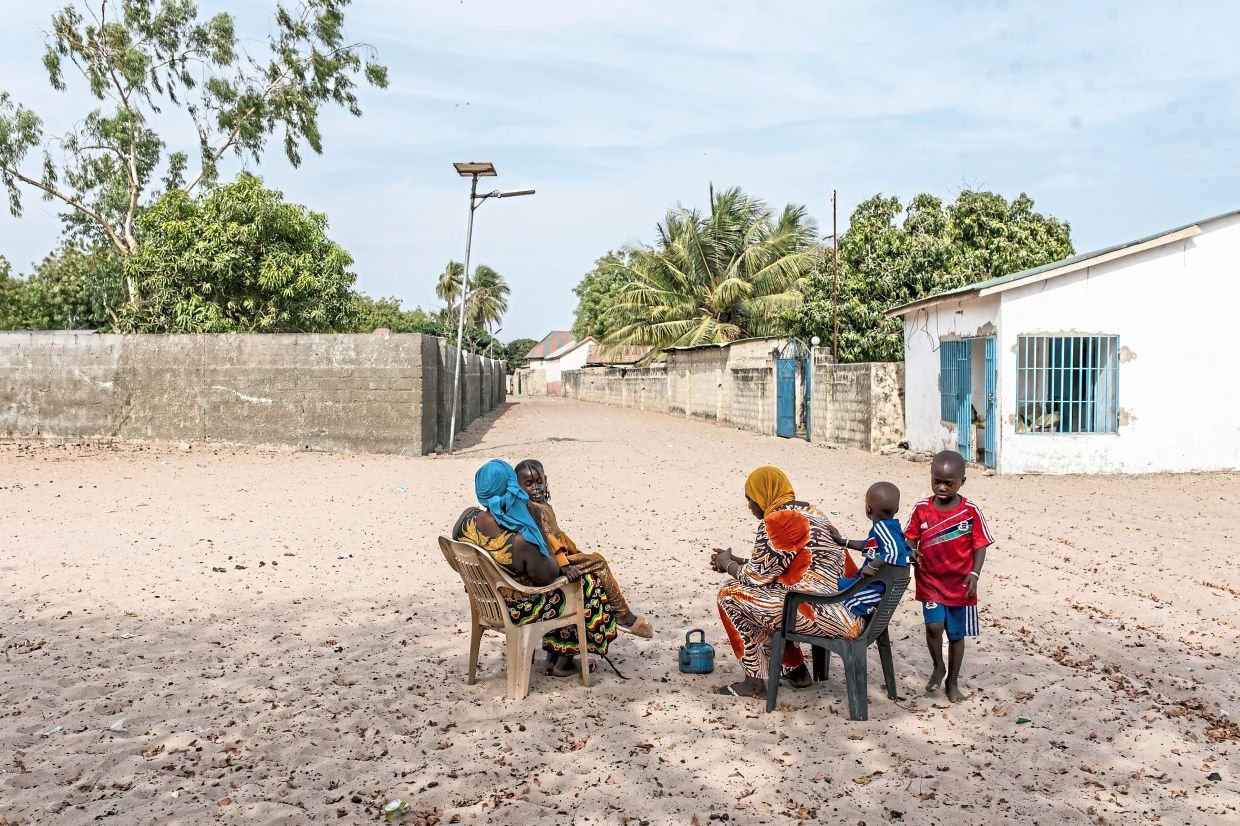 Two women sitting with their children under a tree on Jinack island in Gambia. — Muhamadou Bittaye/The New York Times