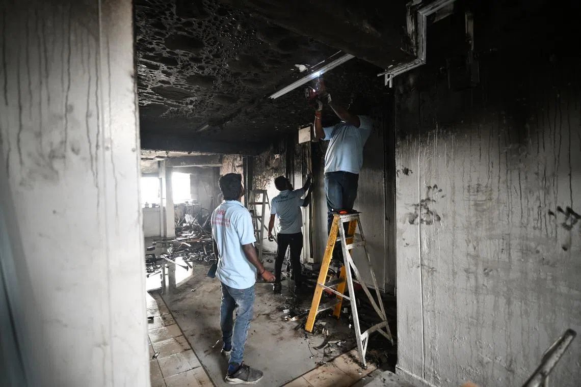 Electrical contractors fixing the wiring on the 18th floor of Block 14 Joo Seng Road on May 5. - Photo: ST
