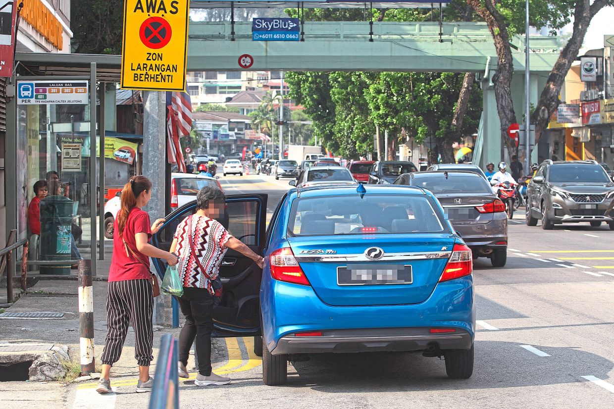 A car stopping by the side of Jalan Jelutong which is marked with double yellow lines to indicate restrictions against stopping or parking.