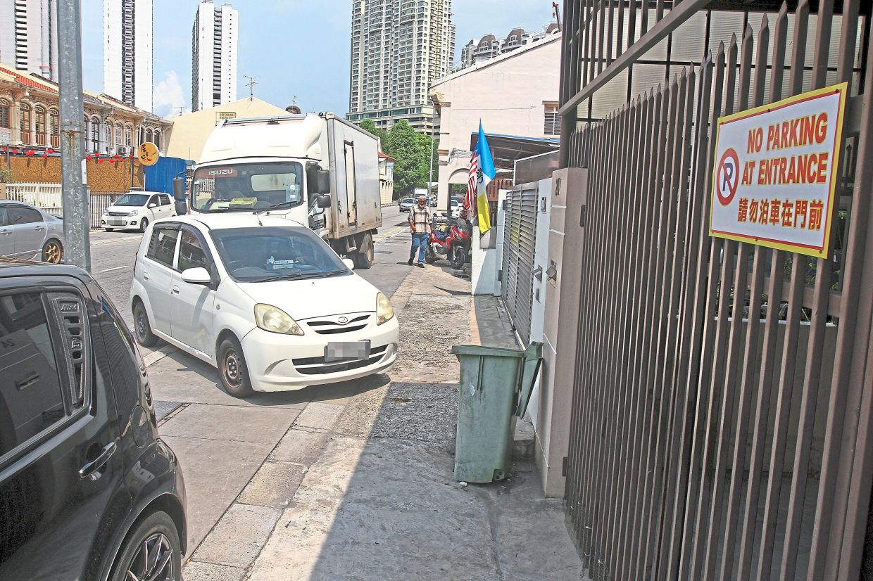 Vehicles blocking a five-foot way and a building entrance in George Town.