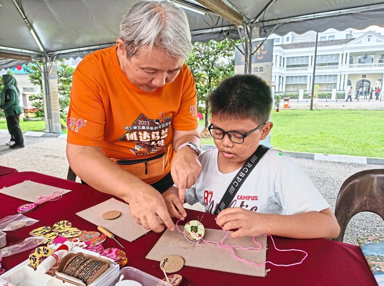 A volunteer guiding a child in crafting an item using recyclable materials, as part of activities in the community cleanup programme.