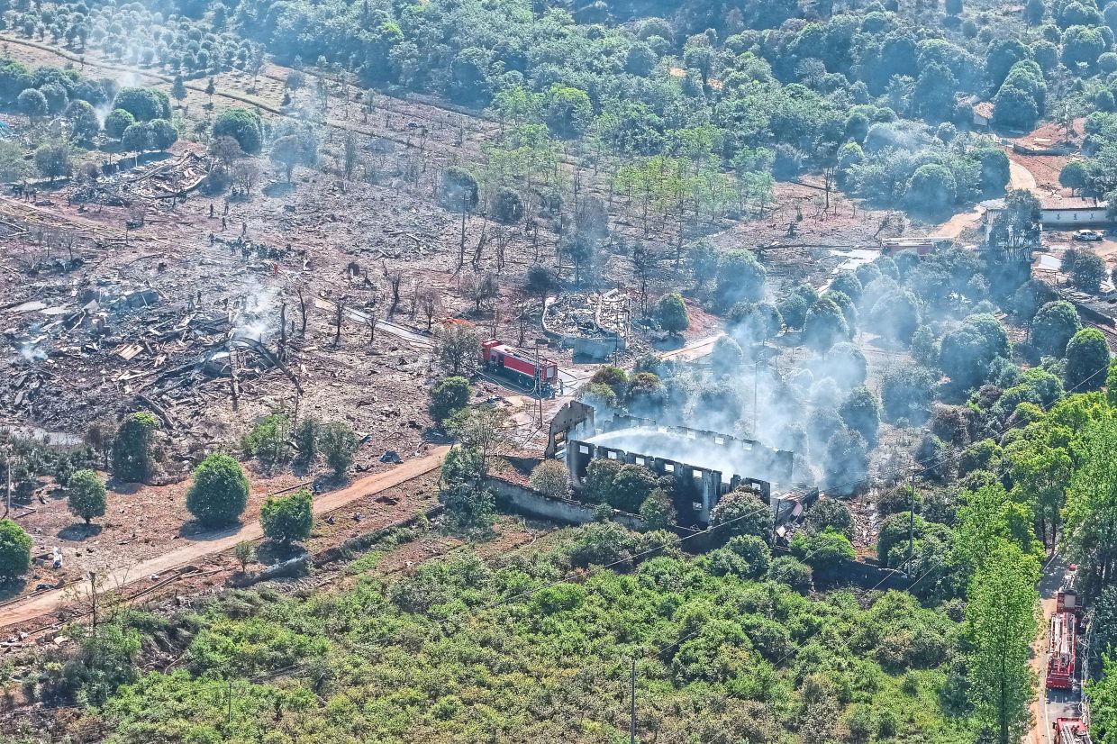 Grim aftermath: Firefighters checking the area and spraying water at embers. — AP