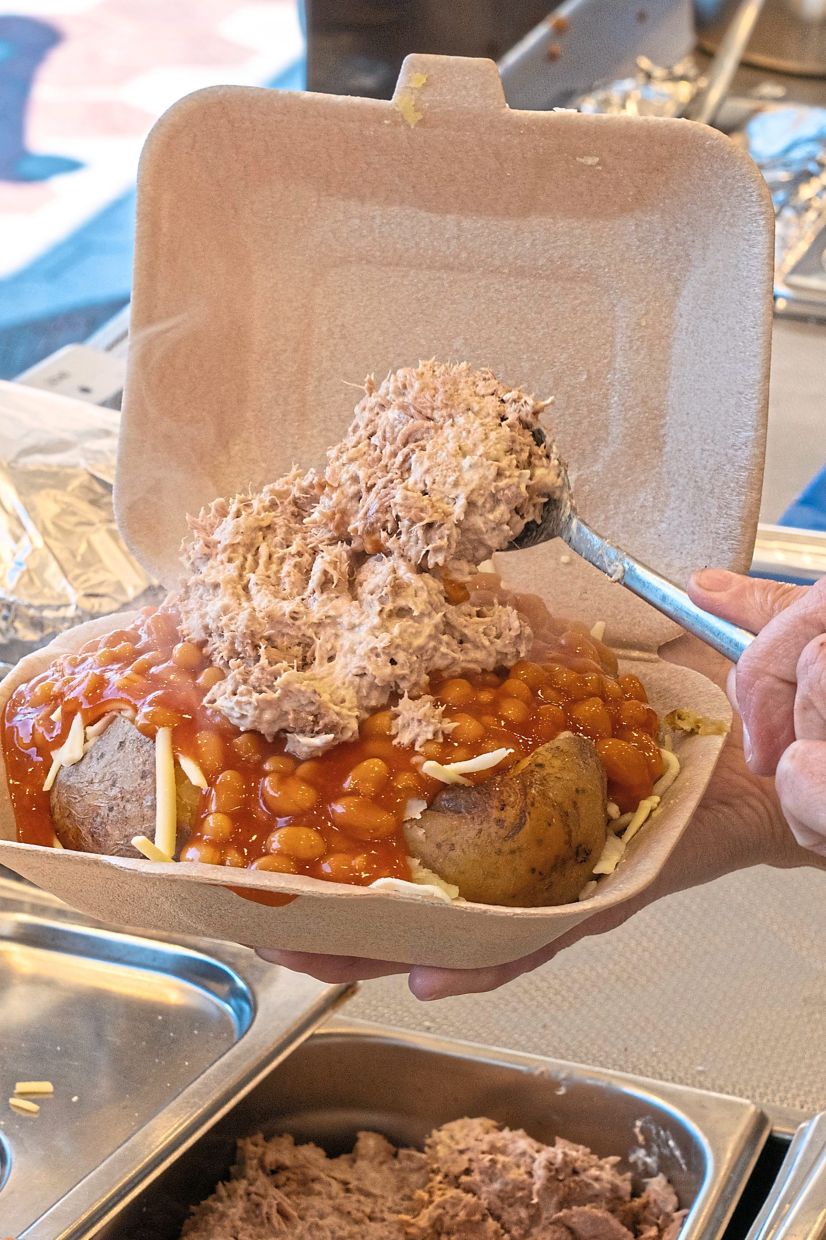 A jacket potato is prepared at the original location of Spudman in a town square in Tamworth, England, March 19, 2026. In the jacket potato revival, toppings like doner kebab and salt-and-pepper chicken have joined traditional favorites like beans and tuna salad. (Chiara Luxardo/The New York Times)