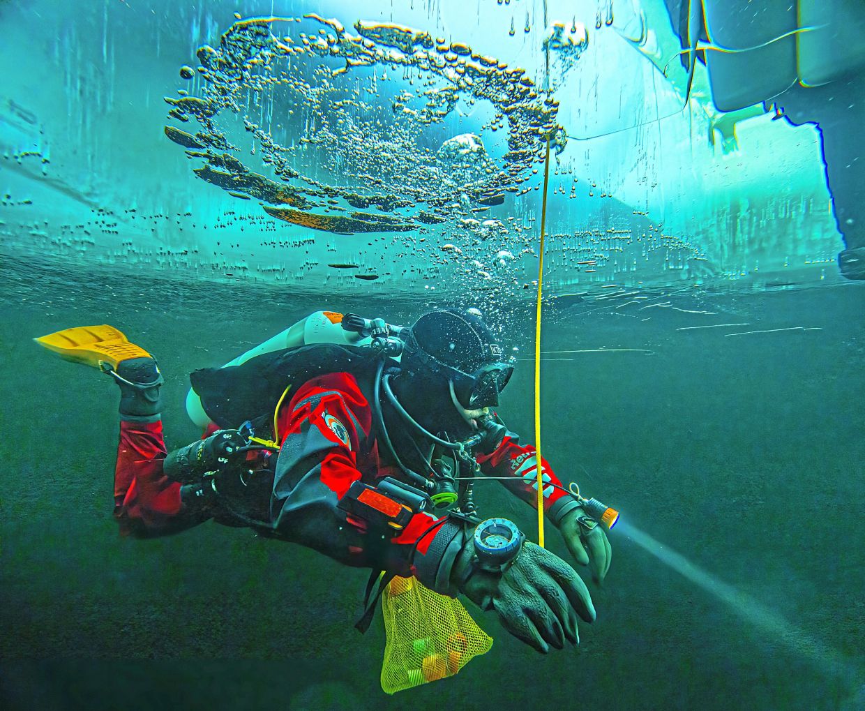 A diver swims under the ice during a Polar Scientific Diving class.