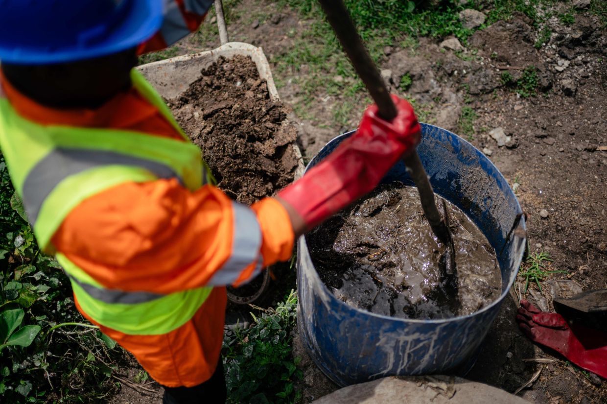 Victoire Materanya, co-founder of Umoja, mixes waste from a duck enclosure to put in the digester in order to produce clean energy.