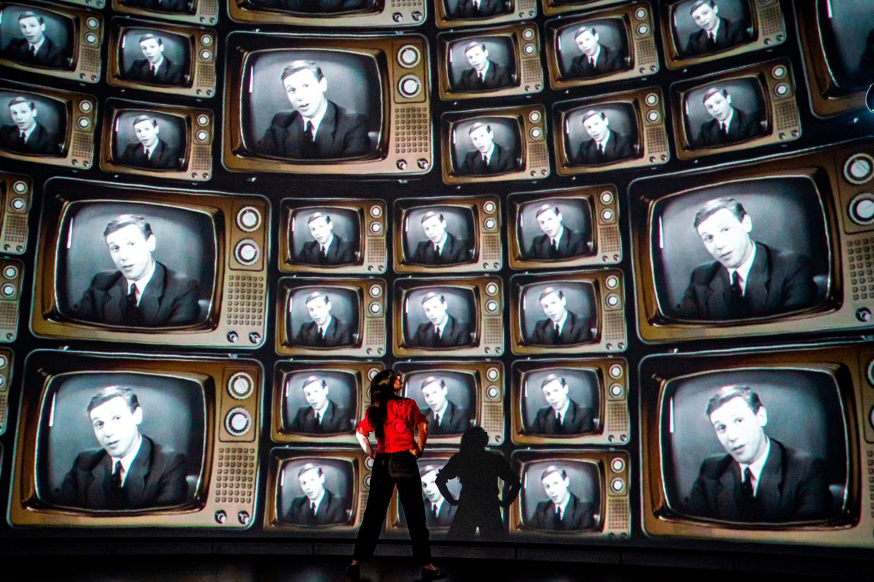 Head of creative enterprise, Maddie Hall, watches hundreds of television screens with broadcaster and naturalist David Attenborough's face, from when he was a young broadcaster, projected on a 360 degree screen inside the dome within the Market Hall ahead of a public release of an immersive film to mark his 100th birthday on May 8, at Real Ideas in Devonport, Plymouth, England. Photo: AP