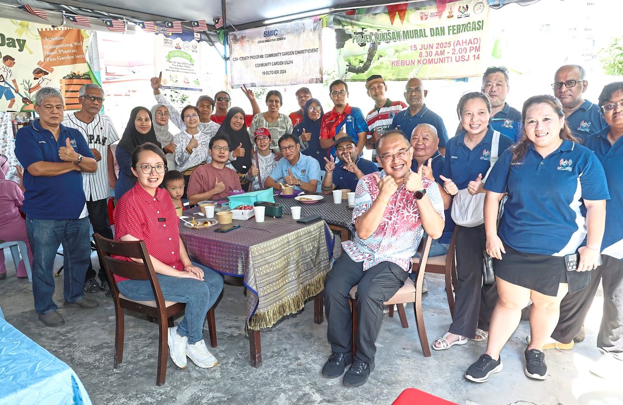 Ng (seated, left), Wong (seated at table, third from left) and Chia (seated, right) with volunteers during the community garden’s anniversary celebration. 
