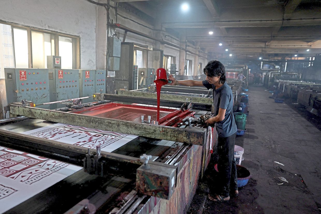 A worker pouring dye to print polyester cloth inside the dyeing unit of Bindal Silk Mills in Surat, Gujarat. — Reuters