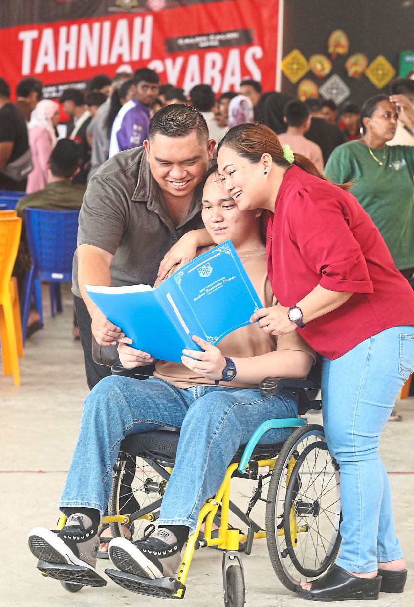 Full of smiles: Fernandez looking at his SPM results with his parents Steven Jaya and Roselind Jelanan. 