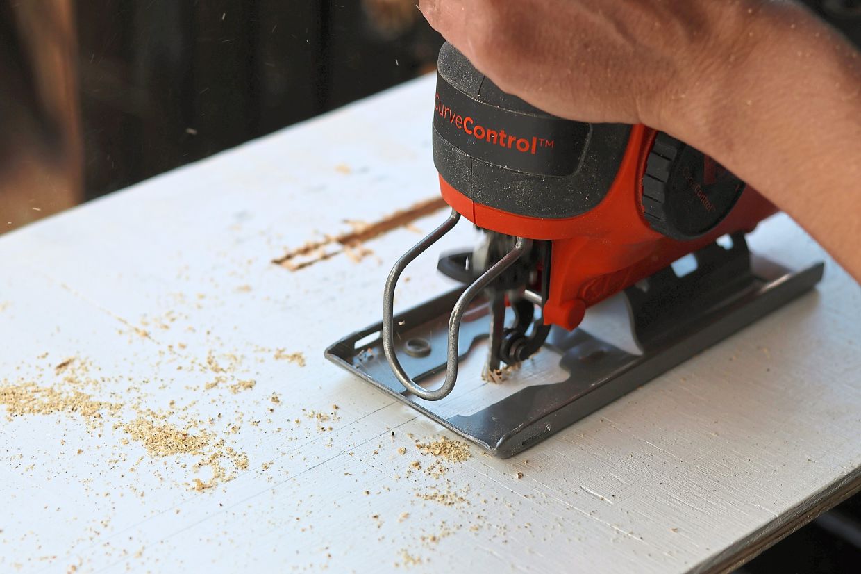 Felicia Fonseca uses a jigsaw to cut slits into a piece of plywood for a wedding sign at a do-it-yourself party at an apartment in Flagstaff, Arizona.. Photos: AP