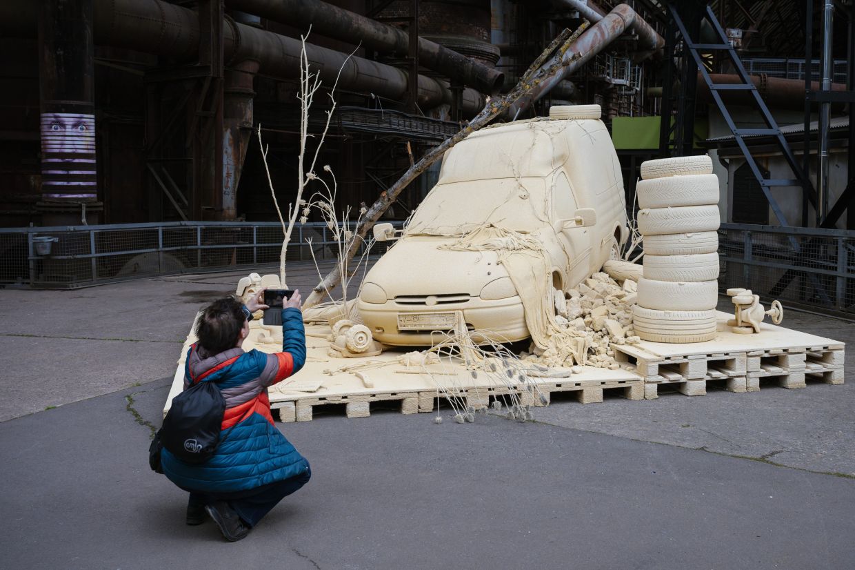 A visitor takes a photo of the installation 'Les Silence des Departs' by artist Tomas Lacque at the Urban Art Biennale 2026. Photo: AP