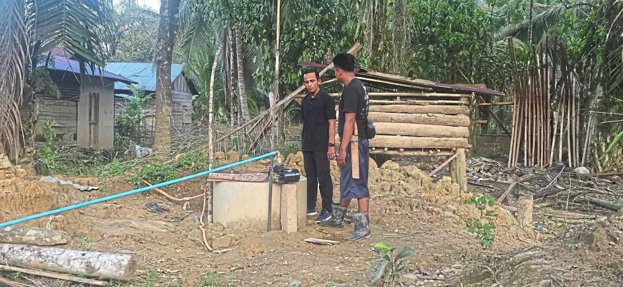 Abdul Rahman (left) and Seri Widayat in Kampung Sulom, checking out one of the many wells contaminated by the deluge.