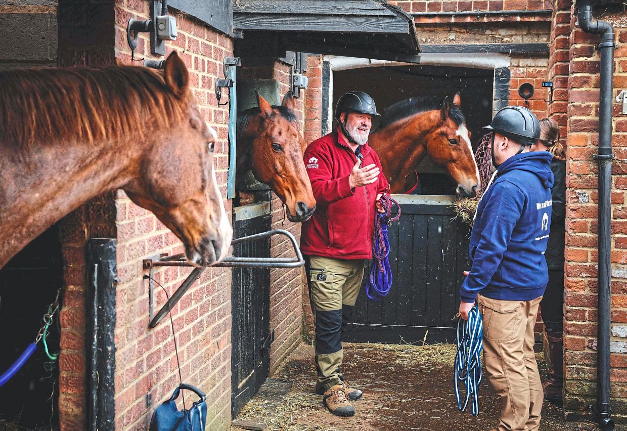 Goddard (left) explains his techniques to gain the trust of a horse to Morton.
