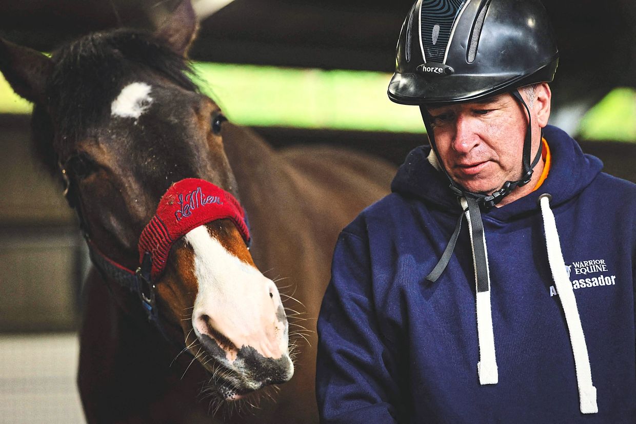 Lewis, who broke several bones in an accident, walks alongside a horse while trying to gain its trust, a therapy exercise designed by Warrior Equine.