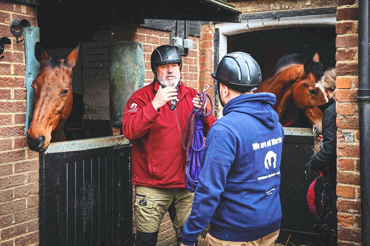 Goddard (left) explains his techniques to gain the trust of a horse to Morton.