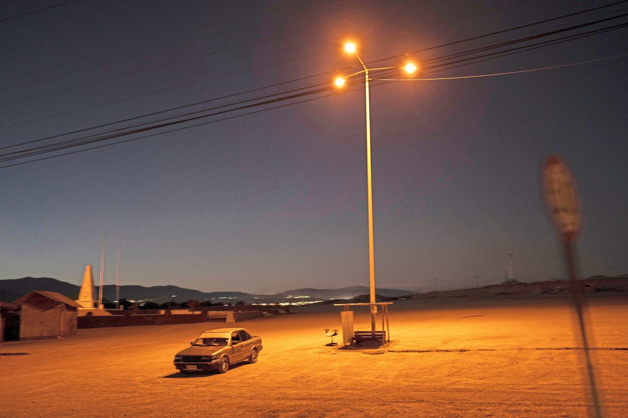 A driver sits in his car in an empty parking lot in Calama, Chile. — AP