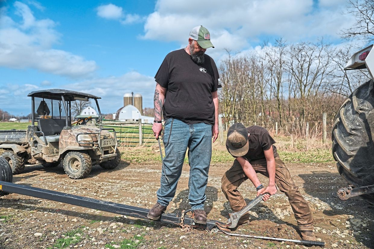 Blake (right) works to repair a hitch as his father helps.